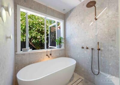 Well-lit bathroom with large open window and deep bath