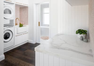 North beach coastal barn laundry renovation with brass, white v groove panelling and pink penny round tiles