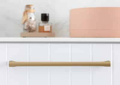 North Beach Coastal Barn Bathroom with brass tapware, pink concrete basins, V Groove panelled cabinetry and Onyx stone look tiles with a feature chevron pattern