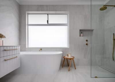 North Beach Coastal Barn Bathroom with brass tapware, pink concrete basins, V Groove panelled cabinetry and Onyx stone look tiles with a feature chevron pattern
