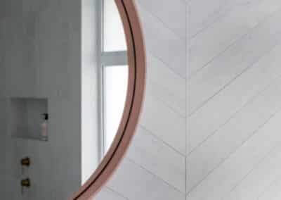 North beach coastal barn bathroom with brass tapware, pink concrete basins, v groove panelled cabinetry and onyx stone look tiles with a feature chevron pattern