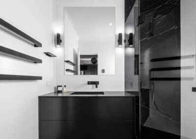 Monochrome ensuite overview with black vanity, feature stone look panels, plenty of light