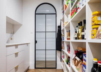 Walk in pantry with fluted arch doorway, marble benchtops and brass hardware