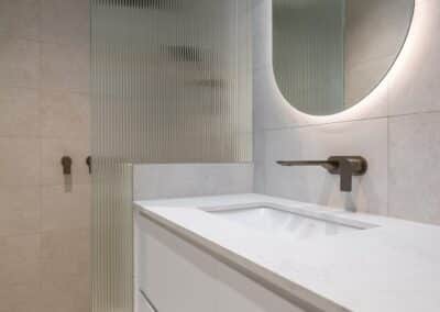 Contemporary ensuite renovation with curved fluted shower screen, featuring brushed nickel tapware