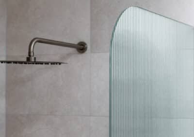 Curved fluted shower screen and brushed nickel shower head