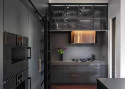 Industrial style kitchen renovation with black cabinetry and lighting, bronze rangehood