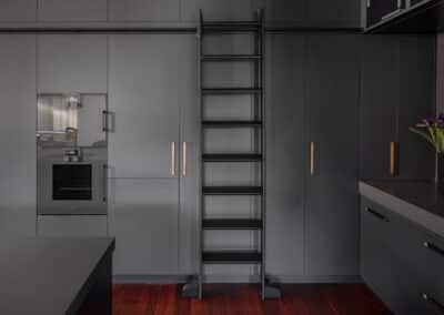 Industrial style kitchen renovation with black cabinetry and rolling library ladder