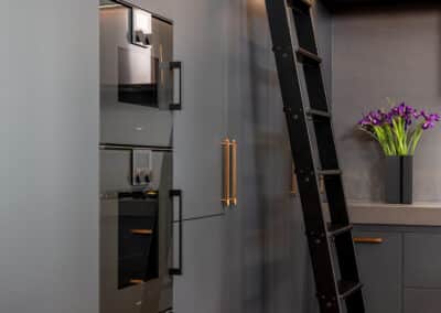 Industrial style kitchen renovation with black cabinetry and rolling library ladder