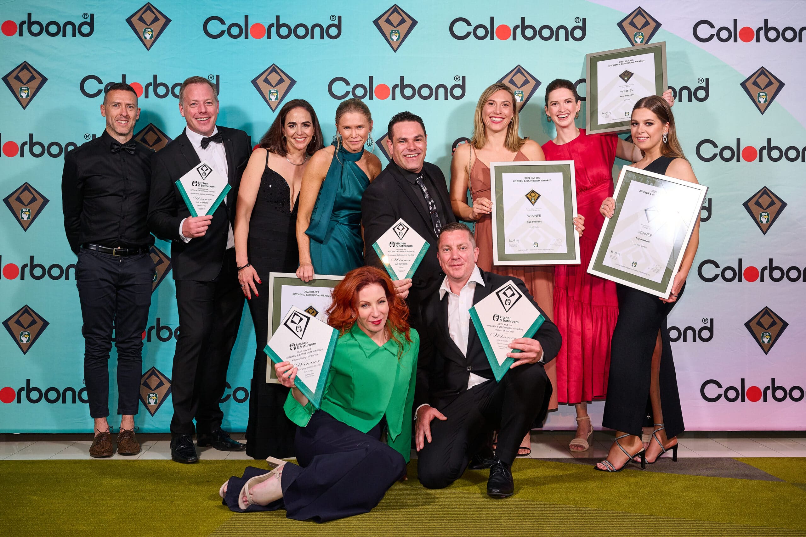 Lux interiors team happily holding up their 7 awards in front of the hia media wall