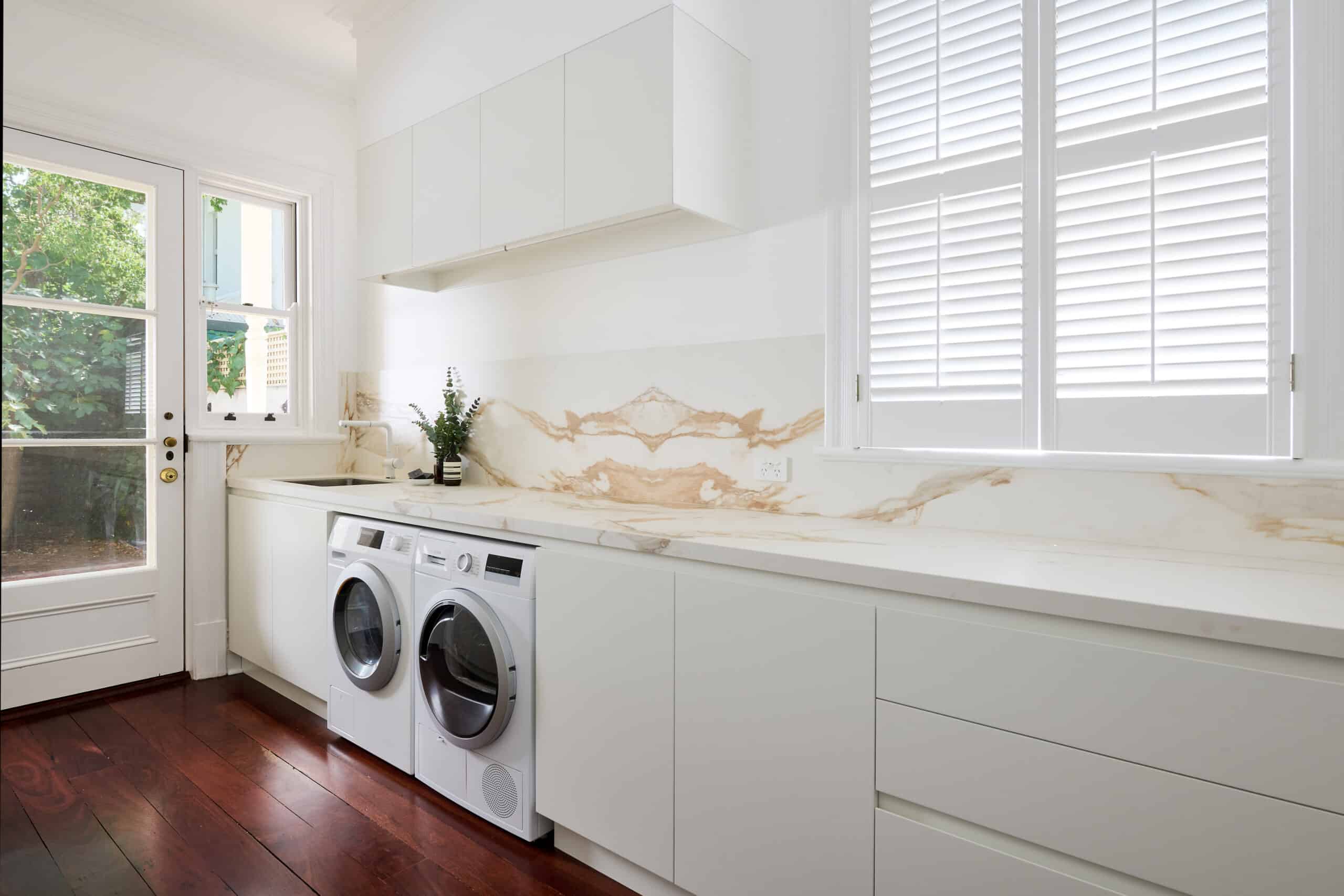 Renovated contemporary laundry with a warm marble look benchtop and seamless cabinetry