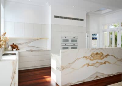 Riley project kitchen renovation with seamless minimalist cabinetry design and a marble look bookmatched island bench on angle