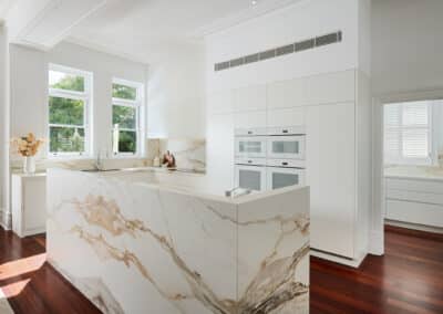 Riley Project kitchen renovation with seamless minimalist cabinetry design and a marble look bookmatched island bench on right angle