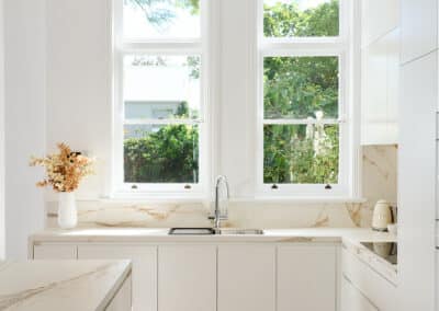 Riley Project kitchen renovation with seamless minimalist cabinetry design and a marble look bookmatched island bench close up of sink and window