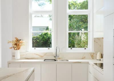 Riley project kitchen renovation with seamless minimalist cabinetry design and a marble look bookmatched island bench close up of sink and window