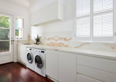 Contemporary warm marble look bookmatched benchtop and splashback and seamless light cabinetry for the new renovated laundry