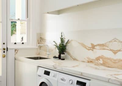 Contemporary warm marble look bookmatched benchtop and splashback and seamless light cabinetry for the new renovated laundry close up